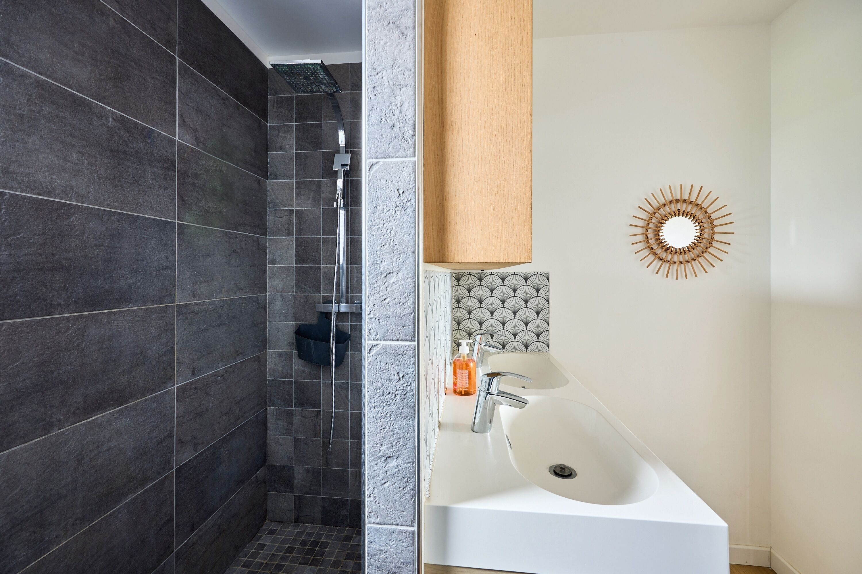 A modern bathroom with a shower, a sink, and a decorative mirror.