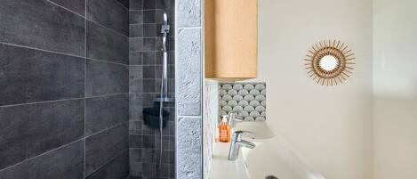 A modern bathroom with a shower, a sink, and a decorative mirror.