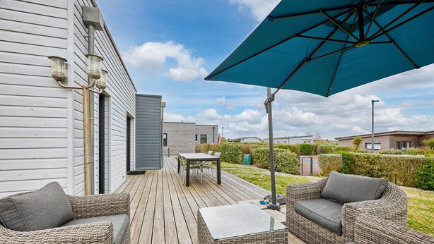 A wooden deck with wicker furniture, a table, and a blue umbrella.