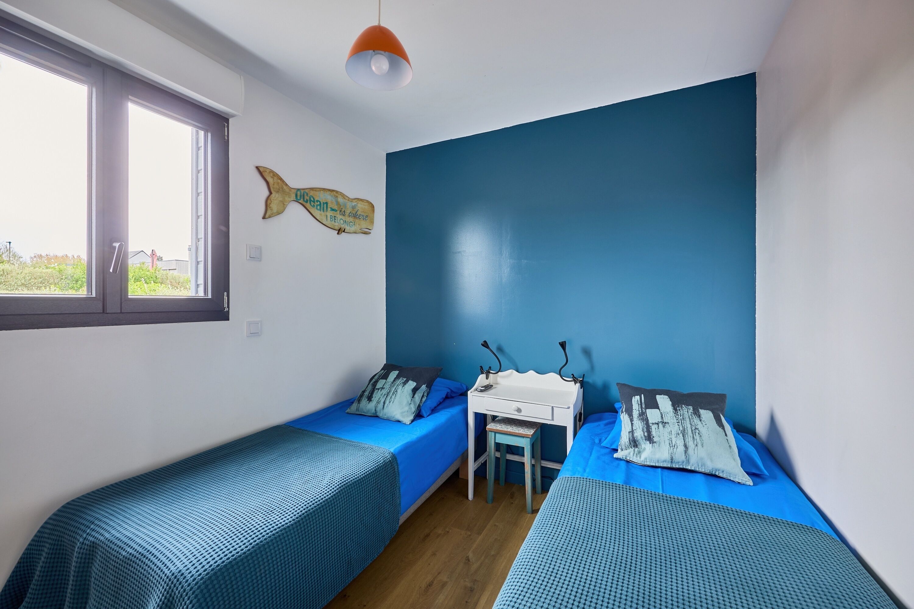 Une chambre avec deux lits simples, un bureau et une chaise.
