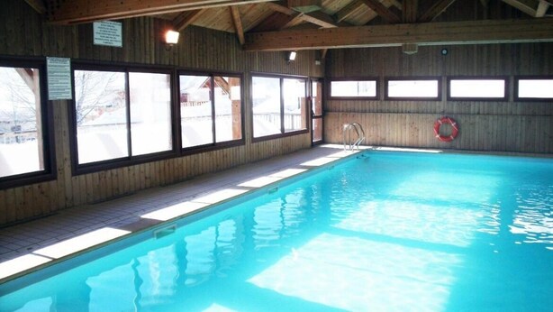 An indoor swimming pool with wooden walls and large windows.