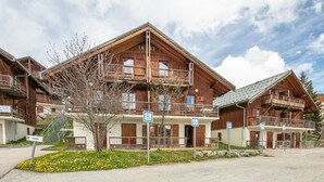 A wooden chalet-style building with balconies, a staircase, and a parking sign.