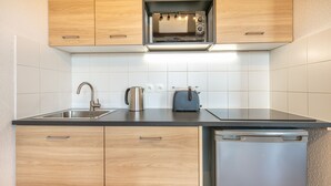 A modern kitchen with wooden cabinets, a built-in microwave, a kettle, and a toaster.