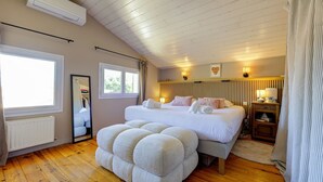 Une chambre avec un grand lit, un plafond en bois, un radiateur, un miroir et une table de chevet avec une lampe.