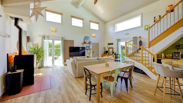 Un vaste espace de vie doté d’un plancher en bois, d’une table à manger et d’un escalier.