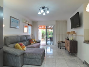 Relax in this stylish living room with a comfortable sofa, flat-screen TV, and sliding glass door leading to an outdoor patio.