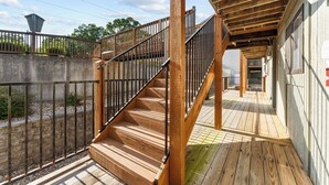A wooden staircase with metal railings leading to a covered outdoor area. - Cozy Romance Vibes! 1 mile from Silver Dollar City-2 Pools-Free Boat Parking  (Reeds Spring, Mo)