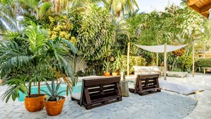 An outdoor patio with a pool, surrounded by lush tropical plants and wooden furniture. - Kibayo Lagoon Villa in Cabarete (Sosúa)