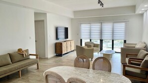 A modern living room with a sofa, chairs, a dining table, and a TV. - 2-bedroom apartment, sea view terrace in marvelous Point Blanche, 2 BA, AC, WIFI (Pointe Blanche)