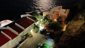 A coastal view at night with a house and parked cars. - 2-bedroom apartment, sea view terrace in marvelous Point Blanche, 2 BA, AC, WIFI (Pointe Blanche)