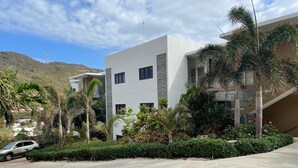 A modern building with multiple balconies, surrounded by lush greenery and palm trees. - 2-bedroom apartment, sea view terrace in marvelous Point Blanche, 2 BA, AC, WIFI (Pointe Blanche)
