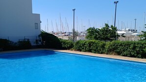 A swimming pool with clear blue water, surrounded by greenery and a white building. - Charming studio with sea view, Gruissan (Gruissan)