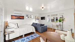 A bedroom with a bed, a gray sofa, a desk, and a chair. - Top Floor SD Bay View Studio in Bankers Hill, San Diego! (San Diego)