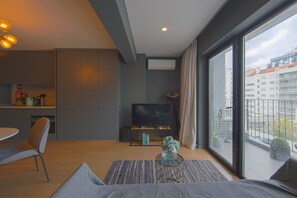 A modern living room with a sofa, a coffee table, a TV, and a balcony with a view of buildings. - Saldanha Prime by Homing (Lisbon)