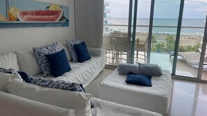 A modern living room with a white sofa and armchairs, a large window with a view of the beach and ocean. - Charming 2-bedroom apartment with WiFi, AC in amazing Cartagena De Indias (Cartagena De Indias)