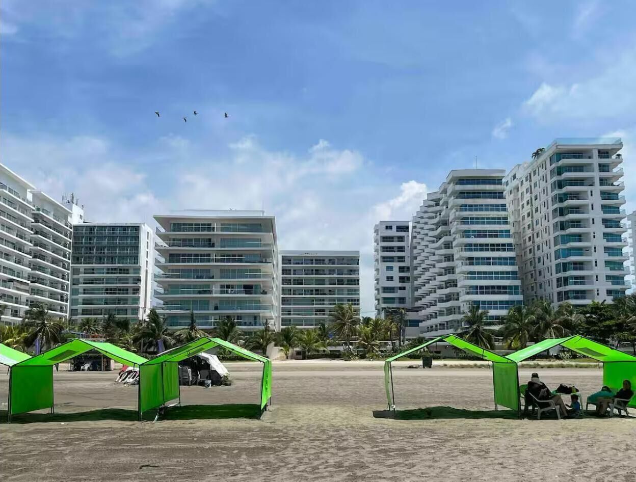 Une zone située en bord de mer, avec de modernes immeubles de grande hauteur, de vastes espaces verts et un ciel dégagé.