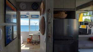 Eine Küche mit Kühlschrank, Telefon und Meerblick durch ein Fenster.