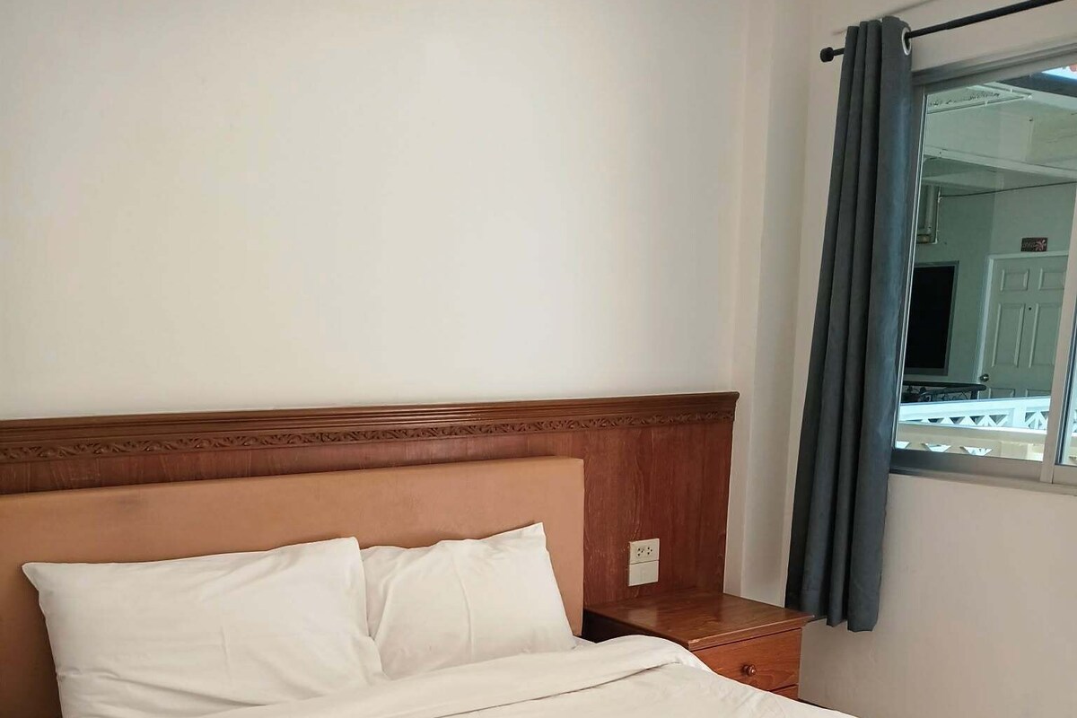 A neatly made bed with white linens and a folded towel on the footboard.