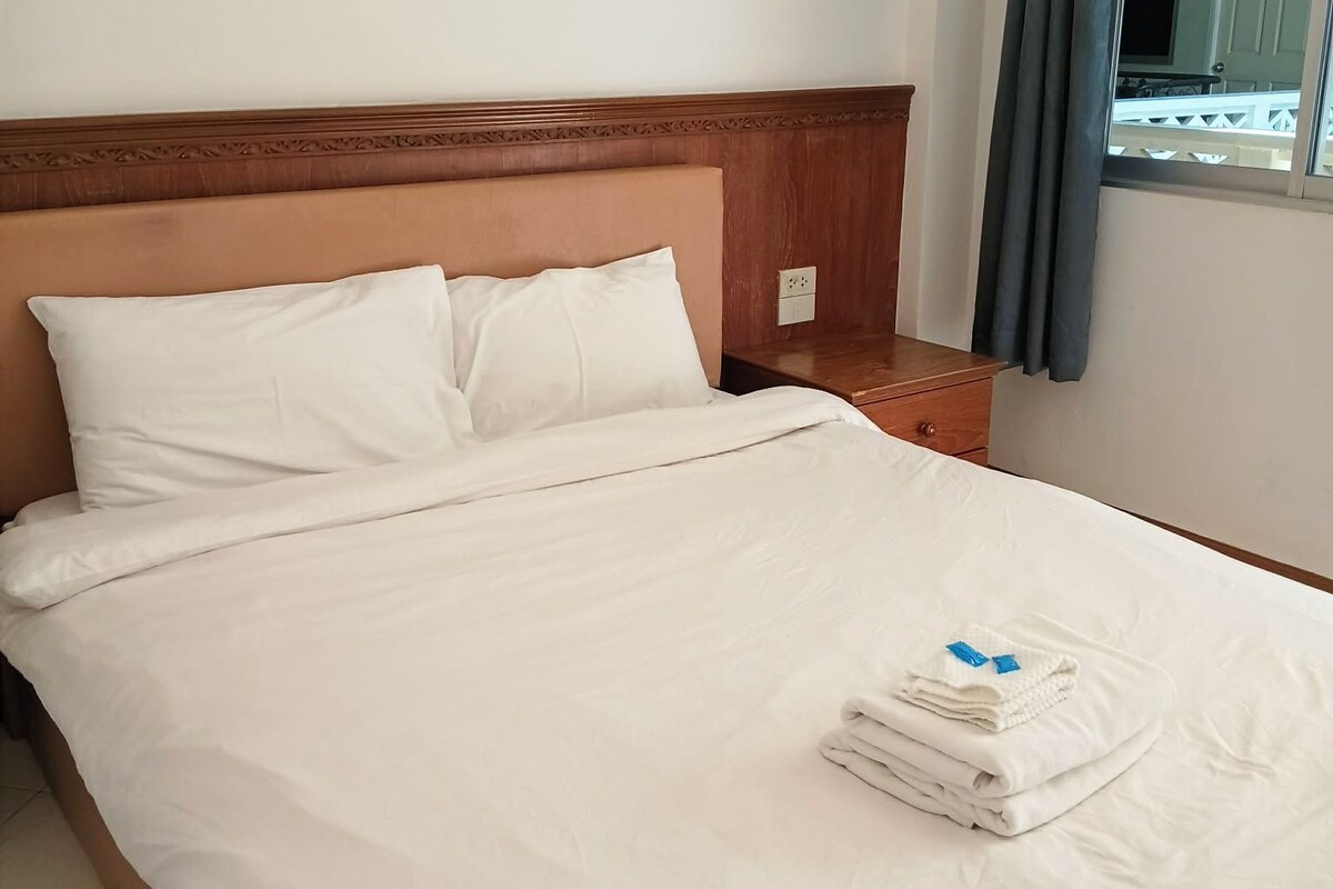 A neatly made bed with white linens and a folded towel on the footboard.