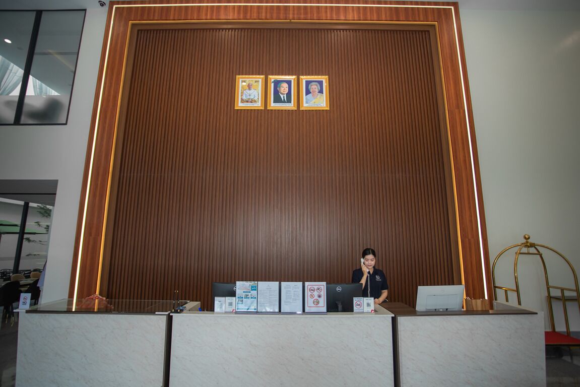 A reception desk with a wooden backdrop and three framed portraits above it.