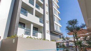 A modern building with multiple floors, balconies, and a pool area. - Nalada Hotel (Ou Chrov)