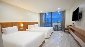 A hotel room with two beds, a desk, a TV, and a balcony with a city view. - Nalada Hotel (Ou Chrov)