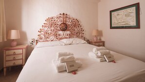 A neatly made bed with white linens, two bedside tables with lamps, and a framed map on the wall.