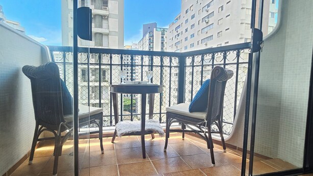 A balcony with two wicker chairs and a small table, surrounded by a metal railing. - Pitangueiras Mar Azul 🌊🌴 your cozy beachfront in Guarujá. (Barra Funda Guarujá)