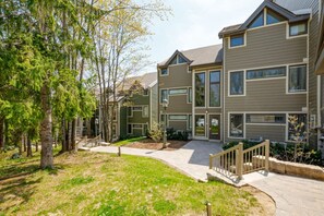 A multi-story residential building with a central courtyard, a covered walkway, and a small outdoor seating area. - Modern Mountain Home for 6 in Chateau Ridge (The Blue Mountains)