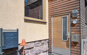 Un bâtiment avec une façade en bois, une porte numérotée et une fenêtre.
