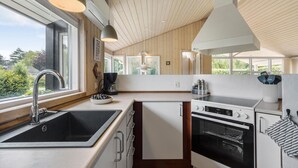 Een moderne keuken met een groot raam, een spoelbak, een fornuis en een koffiezetapparaat.