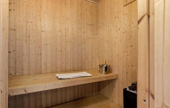 A wooden sauna with a bench, a bucket, and a towel. - Nice home in Ebeltoft with sauna (Ebeltoft)