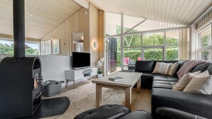 Een moderne woonkamer met een open haard, een televisie, een bank en een eethoek.