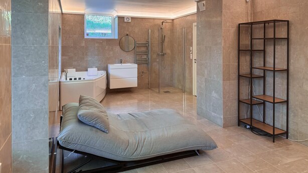 Ein modernes Badezimmer mit Badewanne, Dusche und einer integrierten Regaleinheit.