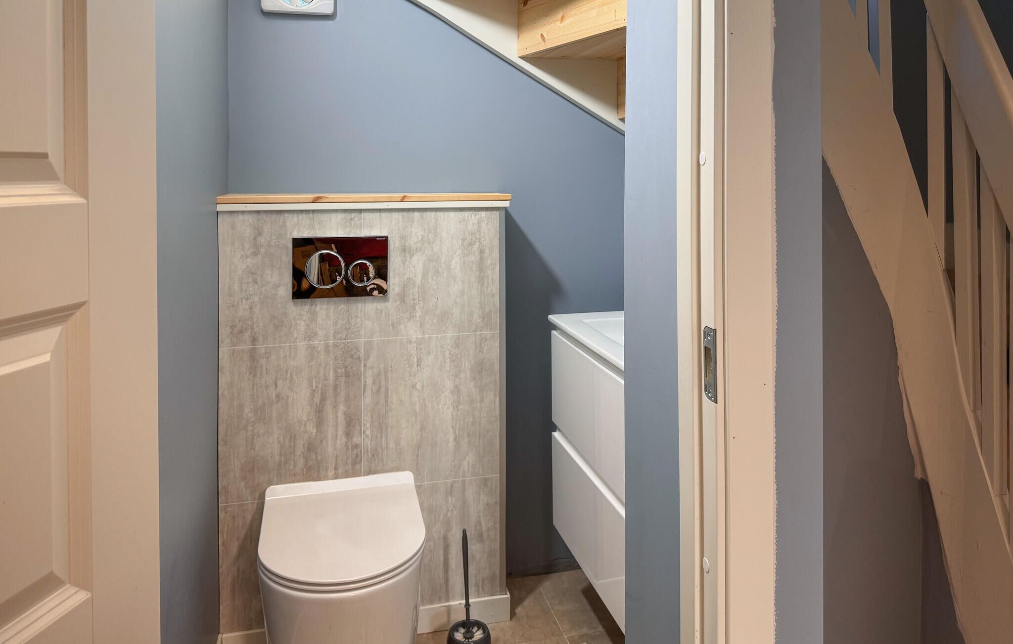 A bathroom with a toilet, a mirror, and a shower area.