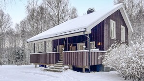 Eine Holzhütte mit überdachter Veranda und einer Treppe, die zum Eingang führt.