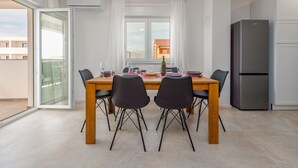 A dining area with a wooden table, black chairs, and a view of a building through a window. - 2 bedroom awesome apartment in Povljana (Povljana)