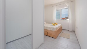 A bedroom with a wooden bed, a window with curtains, and a view of the sky. - 2 bedroom awesome apartment in Povljana (Povljana)