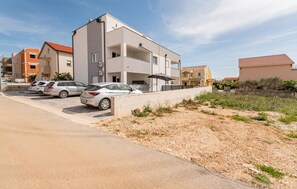 Ein modernes, mehrgeschossiges Wohngebäude mit Parkplatz vor der Tür.