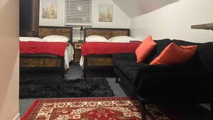 A bedroom with two beds, a black sofa, and a red and white patterned rug. - 2 Pvt bed Rm 1bathroom no kitchen attic (Uniondale)
