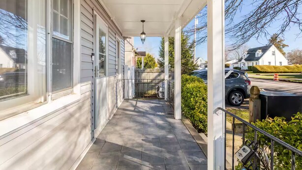 A covered porch with a tiled floor, a hanging light fixture, and a view of a street with parked cars and houses. - 2 Pvt bed Rm 1bathroom no kitchen attic (Uniondale)