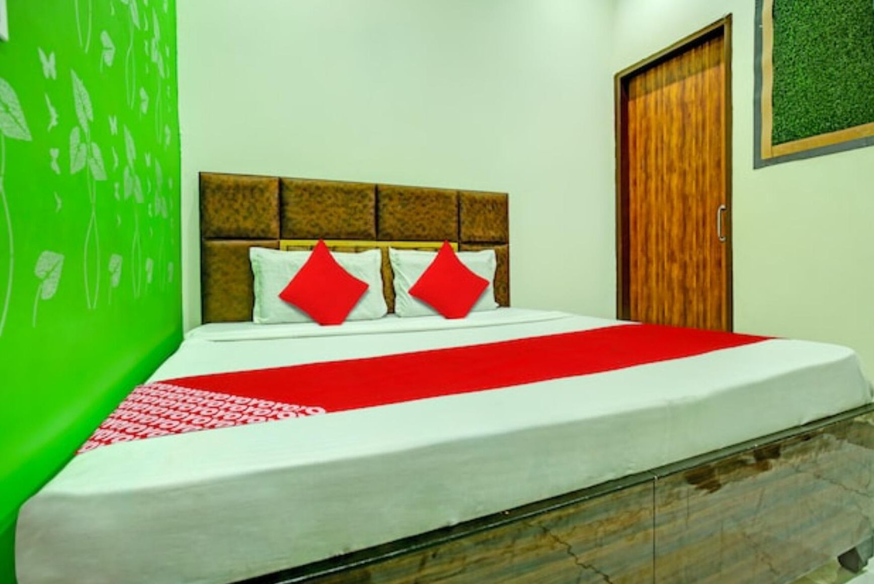 A neatly made bed with a red and white bedspread, two red pillows, and a wooden headboard.