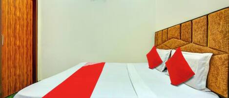 A neatly made bed with a white and red bedspread, a wooden headboard, and a red pillow.