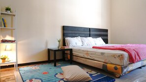 Un dormitorio con cama, mesitas de noche, lámpara, estante con libros y alfombra estampada.