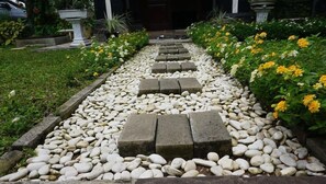 A garden pathway with white pebbles and stepping stones leading to a door. - Green Surabaya Homey (Surabaya)