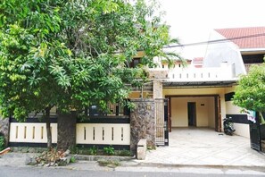 Une maison d’habitation avec une allée carrossable dallée, un pilier en pierre et un portail.