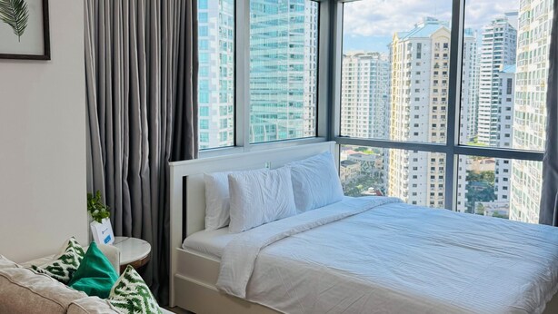 Un dormitorio moderno con una cama grande, un sofá y vistas a rascacielos.