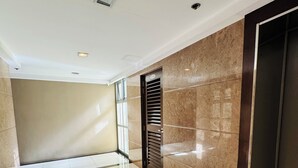 Un pasillo limpio y moderno con un piso de baldosas brillantes, una pared de mármol y una puerta con rejilla.