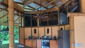 A kitchen with a central island, wooden cabinets, a stove, and a refrigerator. - Finca Viva. Private, tranquil Jungle Oasis! (Uvita Osa)