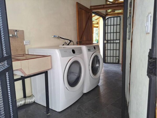 Un área de lavandería con dos lavadoras, un lavabo y un armario de madera.